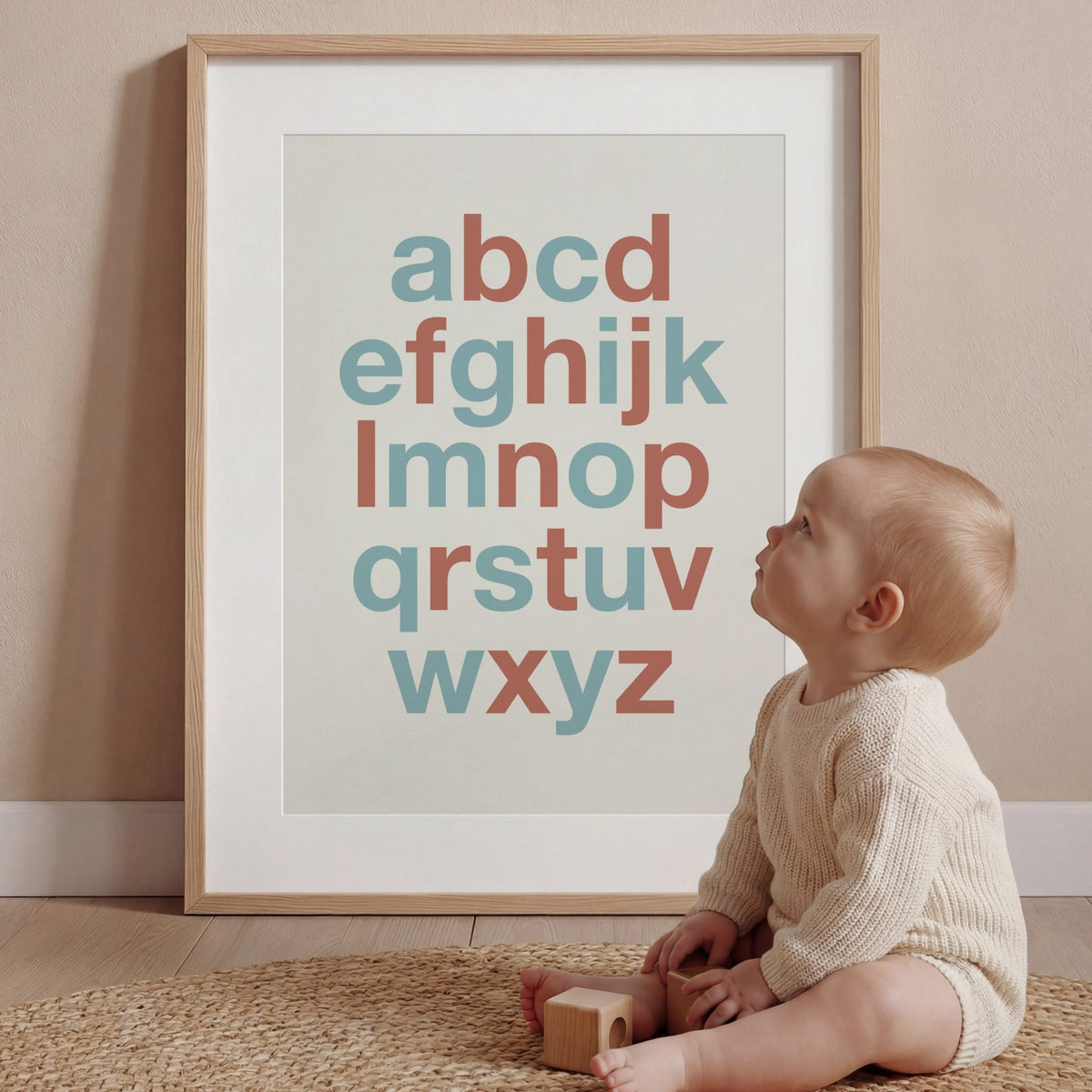 Baby sitting on the floor looking at a framed alphabet poster. | The Crown Prints