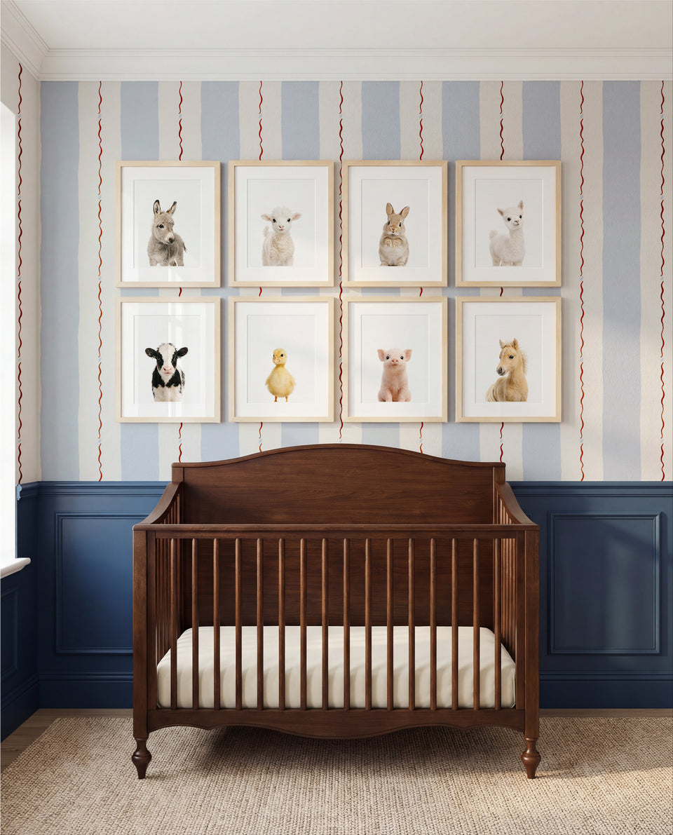 Baby animal prints gallery wall above blue wood crib in styled nursery